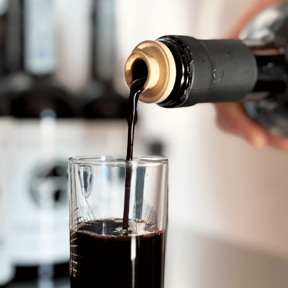 Bicchiere di vetro con liquore alla liquirizia mentre viene versato dalla bottiglia